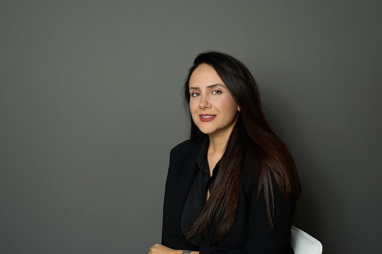 Professional woman posing against a gray background.