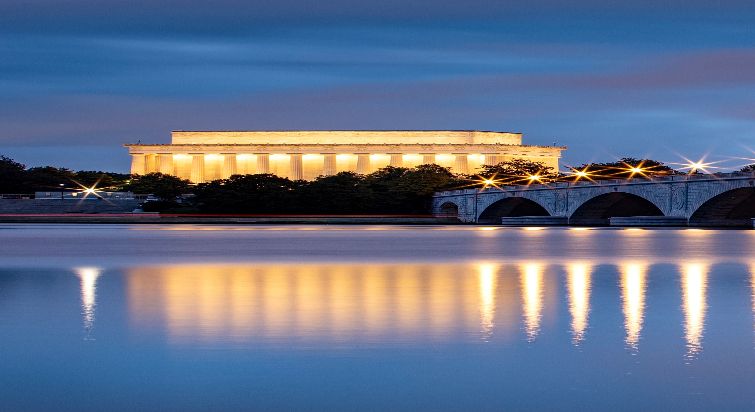 Lincoln Memorial illuminated at dusk, reflecting water.